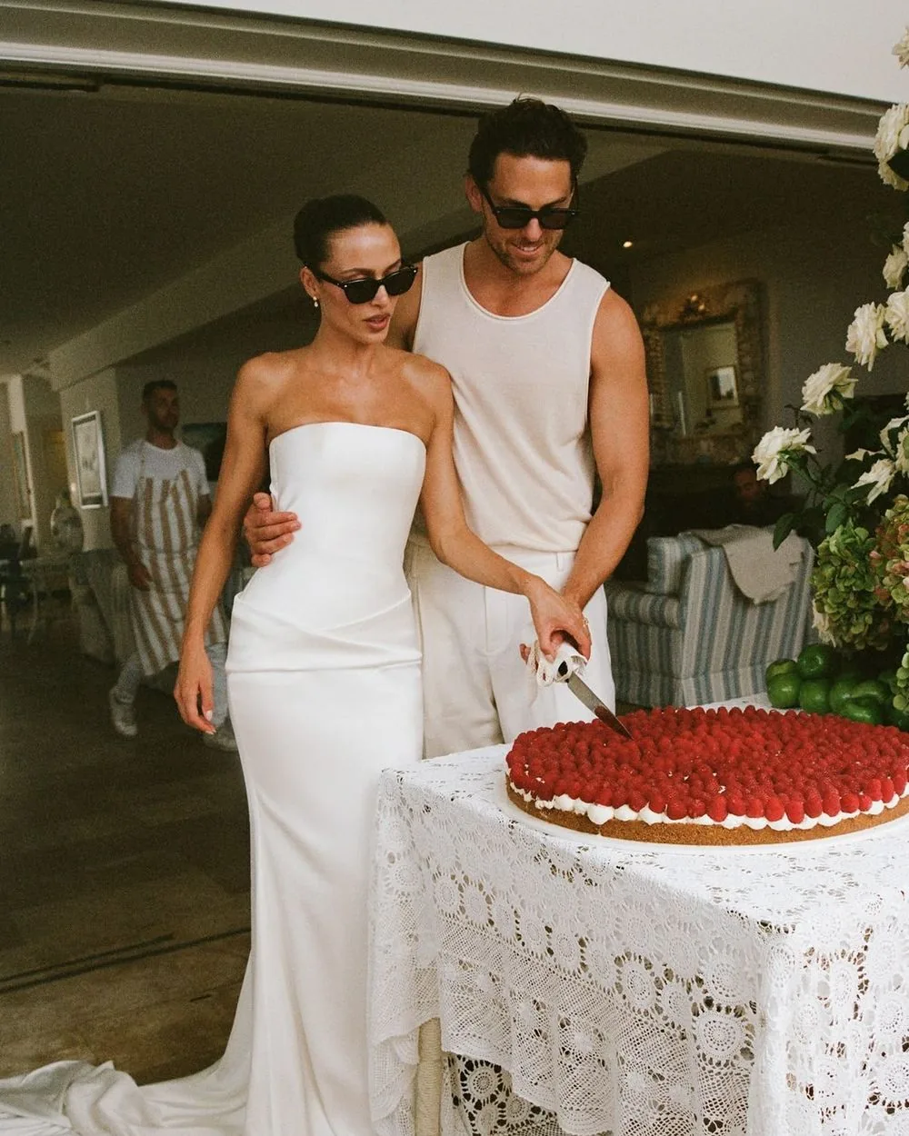 Bride and groom in sunglasses cutting a raspberry cake