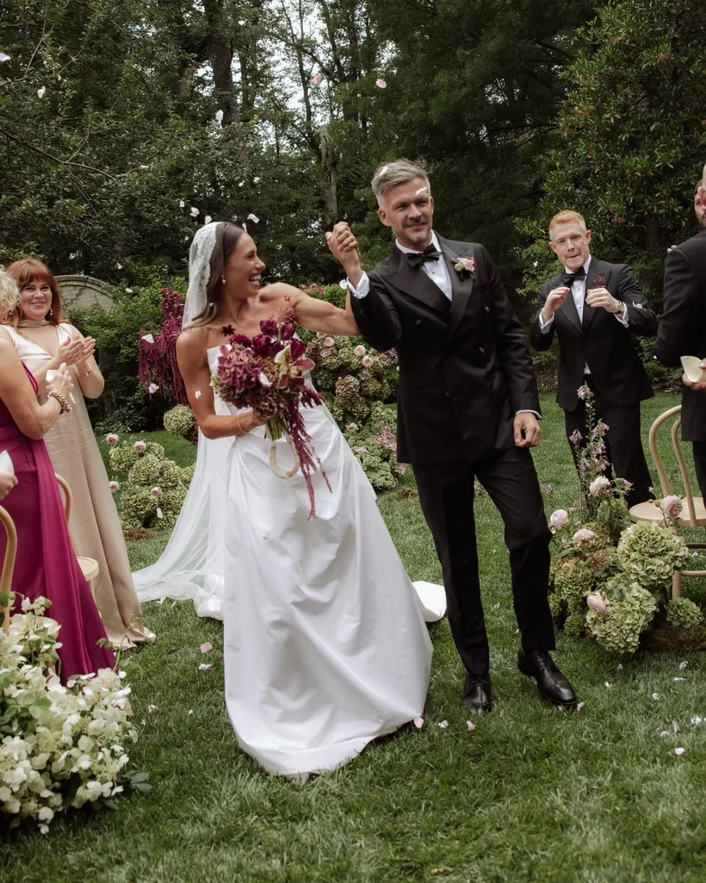 Bride and groom celebrating down the aisle under falling petals