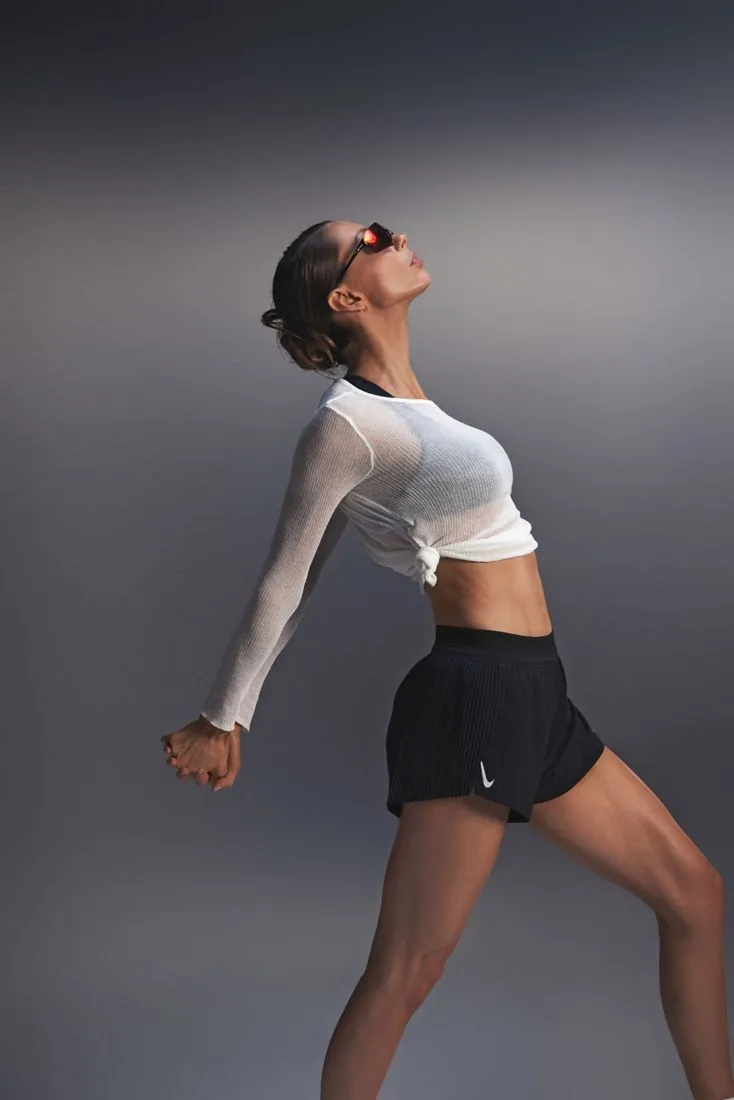 Jules leaning back into a stretch in a white knit top and running shorts